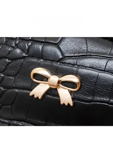 Detail of black crocodile texture leather with a golden butterfly metal buckle charm