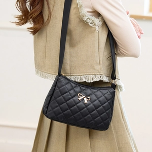 Classic black quilted crossbody bag with golden bow and adjustable strap on model