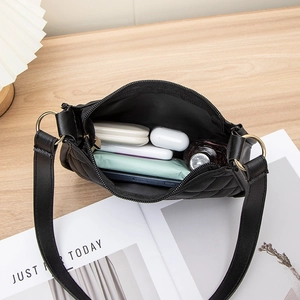 Sac hobo noir matelassé avec anneaux dorés montrant la capacité sur table en bois