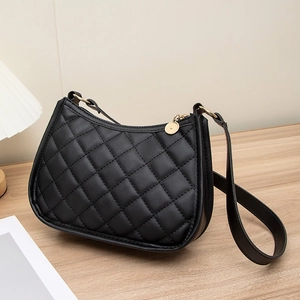 Sac à épaule matelassé noir classique avec détails dorés sur table en bois chic