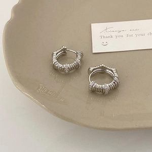 Détail macro de créoles argentées avec finition texturée et pierres de zircon