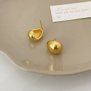 Detailed macro of brushed gold teardrop earrings featuring a textured matte finish