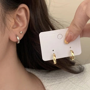 Close-up of minimalist gold and silver hoop earrings on a model with polished mirror finish