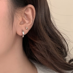 Minimalist silver hoop earrings and ball stud set worn by model in a natural side view