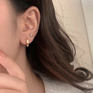 Detailed view of chunky textured gold hoop and simple silver ball stud earring set