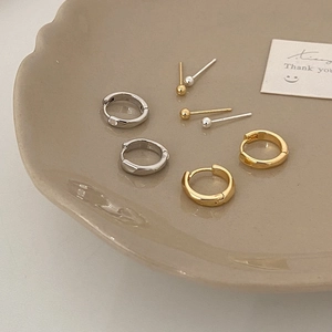 Minimalist gold and silver hoop earrings and ball studs set on a ceramic plate