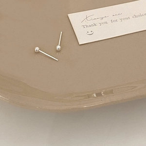 Minimalist silver stud earrings with small polished round beads on a ceramic tray