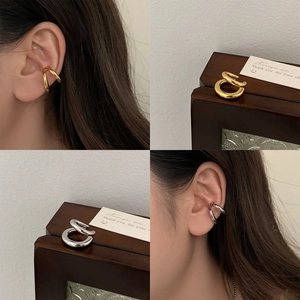 Macro detail of minimalist double-layered ear cuffs in polished gold and silver finishes