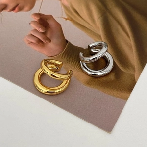 Macro shot of polished gold and silver double-layered ear cuffs on a fashion magazine