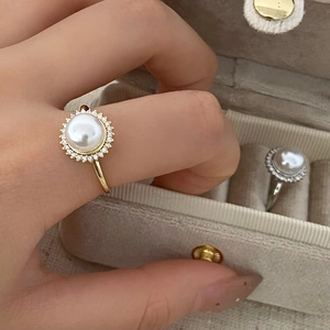 Detail of elegant open ring with large half-round pearl and sparkling zircon halo