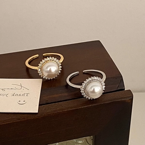Detailed view of two adjustable open rings with large pearls and micro-pave zircon crystals