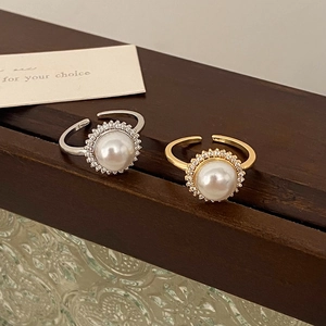 Adjustable pearl rings with zircon halo in gold and silver finish on a wooden display
