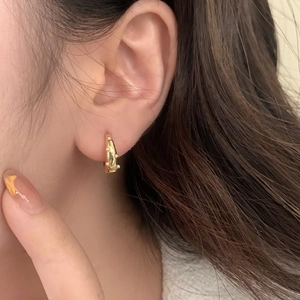 Elegant gold hoop earrings with white pearls shown on a female model's ear lobe