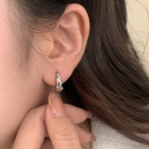 Close-up of irregular textured silver earrings with pearl accents worn by a model