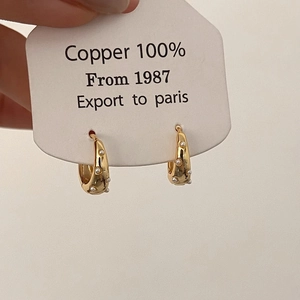 Detail showing wavy textured golden copper earrings with inlaid white imitation pearls