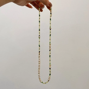 Detail van zoetwaterparelketting met bamboe-stijl kralen en gouden karabijnsluiting