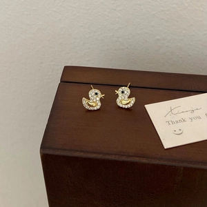 Cute gold duck earrings with pavé zircon stones on a wooden jewelry box display