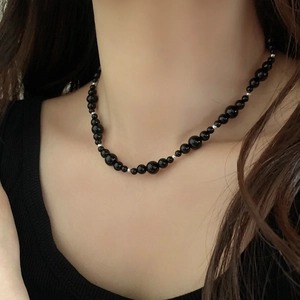 Détail du collier de perles en calcédoine avec œil de tigre et perles noires sur modèle