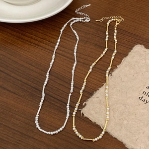 Elegante minimalistische Perlenketten in Gold und Silber auf rustikalem Holzhintergrund