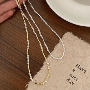Detailansicht minimalistischer Perlenketten in Gold und Silber auf dunklem Holz