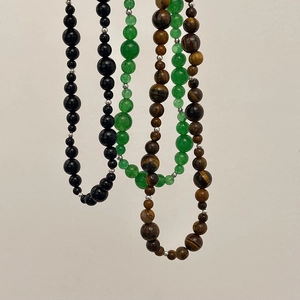 Détail des perles naturelles en calcédoine et œil de tigre sur des colliers épurés