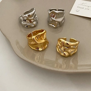 Minimalist liquid metal style wide open rings in gold and silver finish on a ceramic tray
