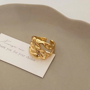 Detailed view of adjustable golden wide ring with irregular lava melt texture on white card