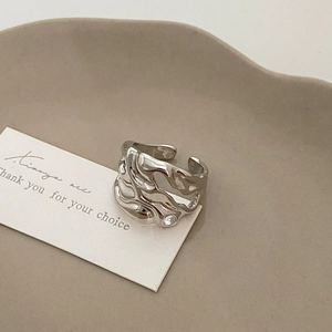 Close-up of a silver irregular textured open ring with minimalist liquid metal ripples