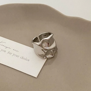 Detail of silver irregular liquid texture ring on beige ceramic display tray