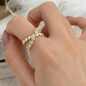 Detail of gold double-layer crisscross ring with heart shapes and sparkling zircon pavé