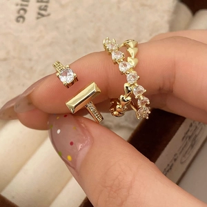 Detail of gold-plated rings featuring a heart-shaped zircon and a T-design with round stone