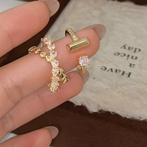 Macro shot of gold micro-pave zircon heart ring and T-shaped adjustable ring on finger
