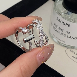 Detail of silver micro-paved zircon heart ring and rectangular gemstone ring on fingers