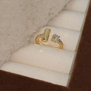 Macro shot of gold adjustable open ring with T-shape design and micro-set zircons