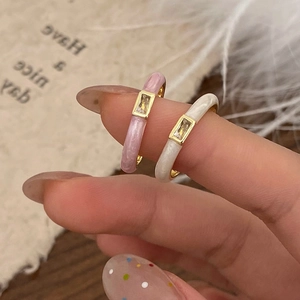 Primer plano de anillos de esmalte crema con circonitas rectangulares en una modelo