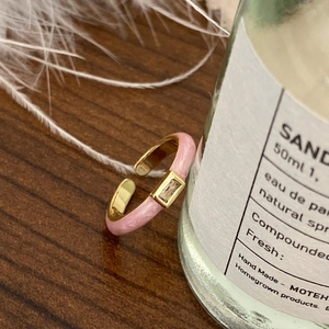 Detalle de anillo dorado con esmalte rosa y una piedra de circonita rectangular