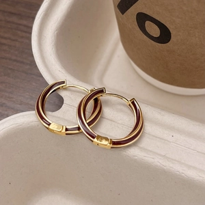 Chic gold-plated hoop earrings with dark red enamel in a minimalist spiral design