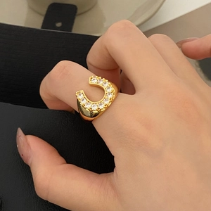 Detail of horseshoe ring with gold plating and pave-set white cubic zirconia on a hand