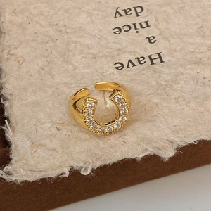 Macro view of gold horseshoe ring with micro-pave cubic zirconia on textured background