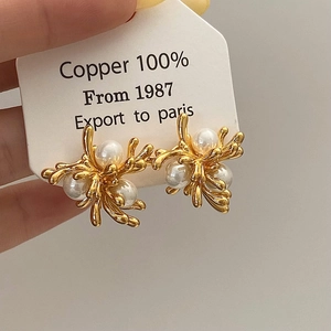 Macro detail of golden metal firework earring with white pearls and 100% copper base