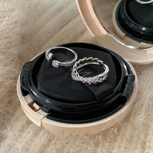Macro detail of silver-tone stackable rings with pavé zircon and T-design on soft plush