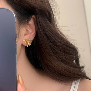 Elegant matte gold flower stud earrings in lily design worn by a female model