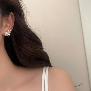 Close-up of a matte silver flower stud earring worn on ear with soft lighting