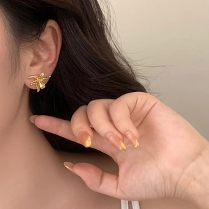 Detail of matte gold irregular flower stud earring worn to show realistic size and texture