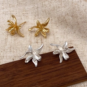 Macro detail of irregular matte metal flower earrings in gold and silver finish