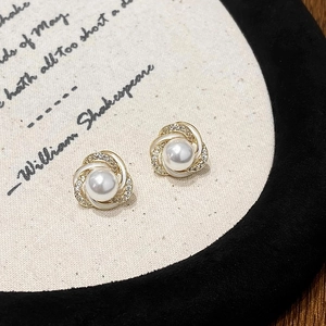 Détail de boucles d'oreilles fleurs dorées avec perles blanches et zircons sur présentoir