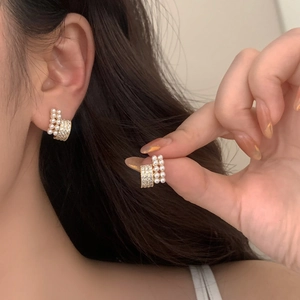 French style C-shaped gold pearl earrings with pave cubic zirconia on model