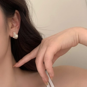 Close-up of elegant French pearl and zircon stud earrings worn on a model's ear