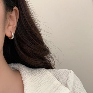 Macro detail of silver star-engraved hoop earring worn on a model for a chic daily look