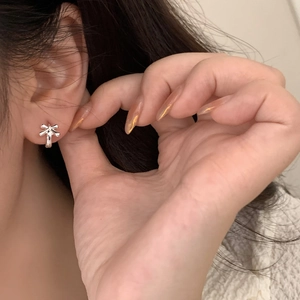 Minimalist silver bow knot stud earrings for women shown worn on the earlobe